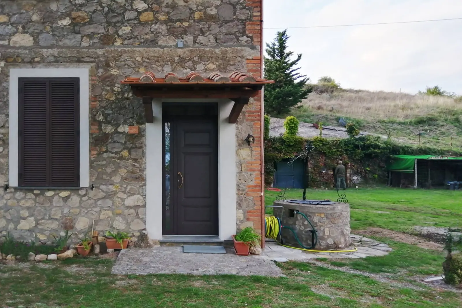 The front door in the stone wall, next to the well