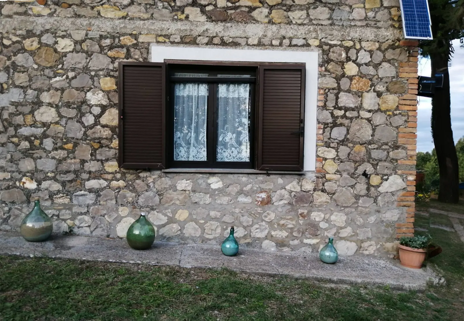 Stone façade with a window and demijohns