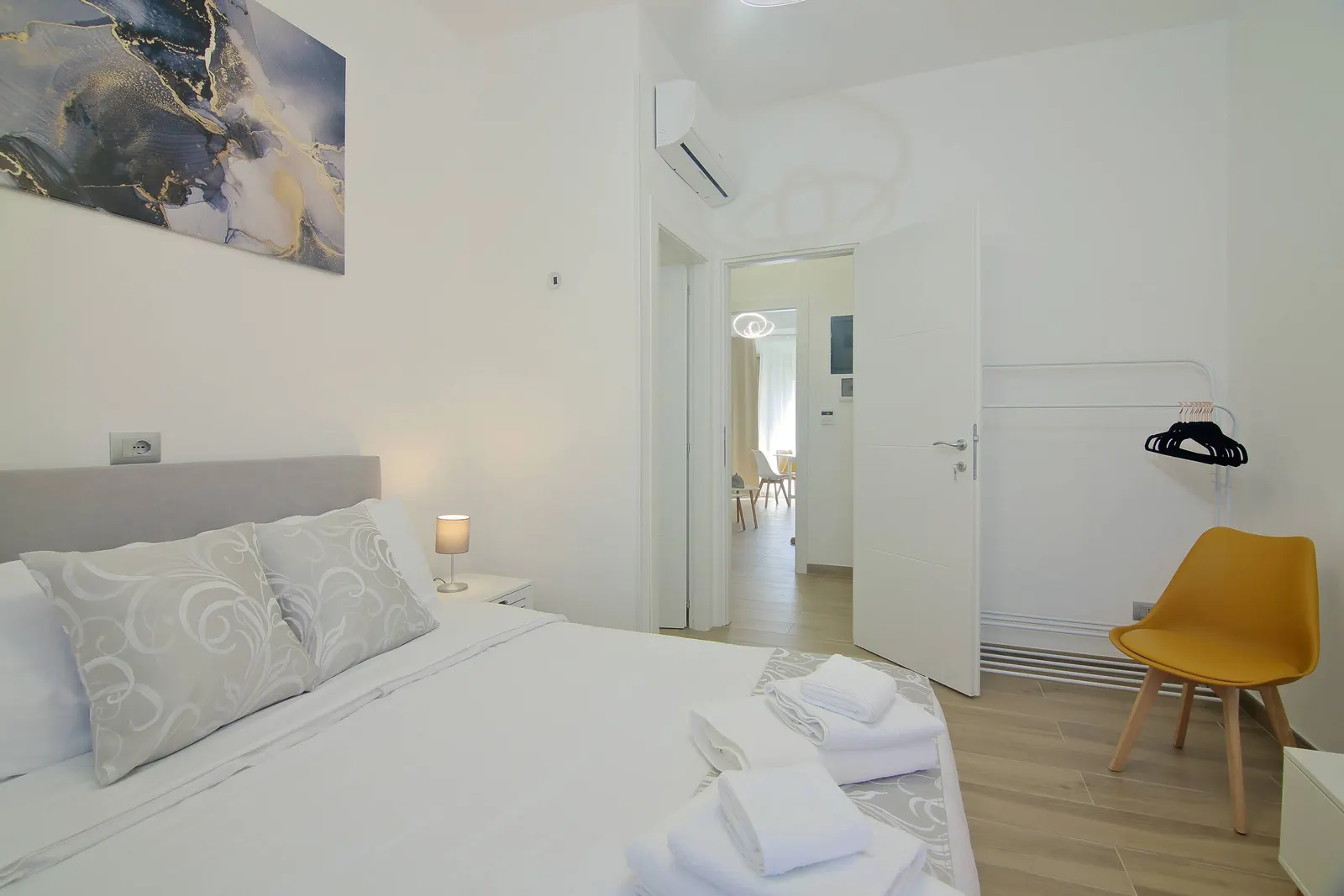 Double bedroom with a yellow chair and a door onto the hallway