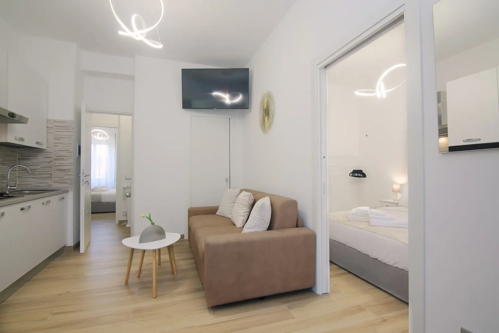 The living room with sofa and TV, and the door to a bedroom