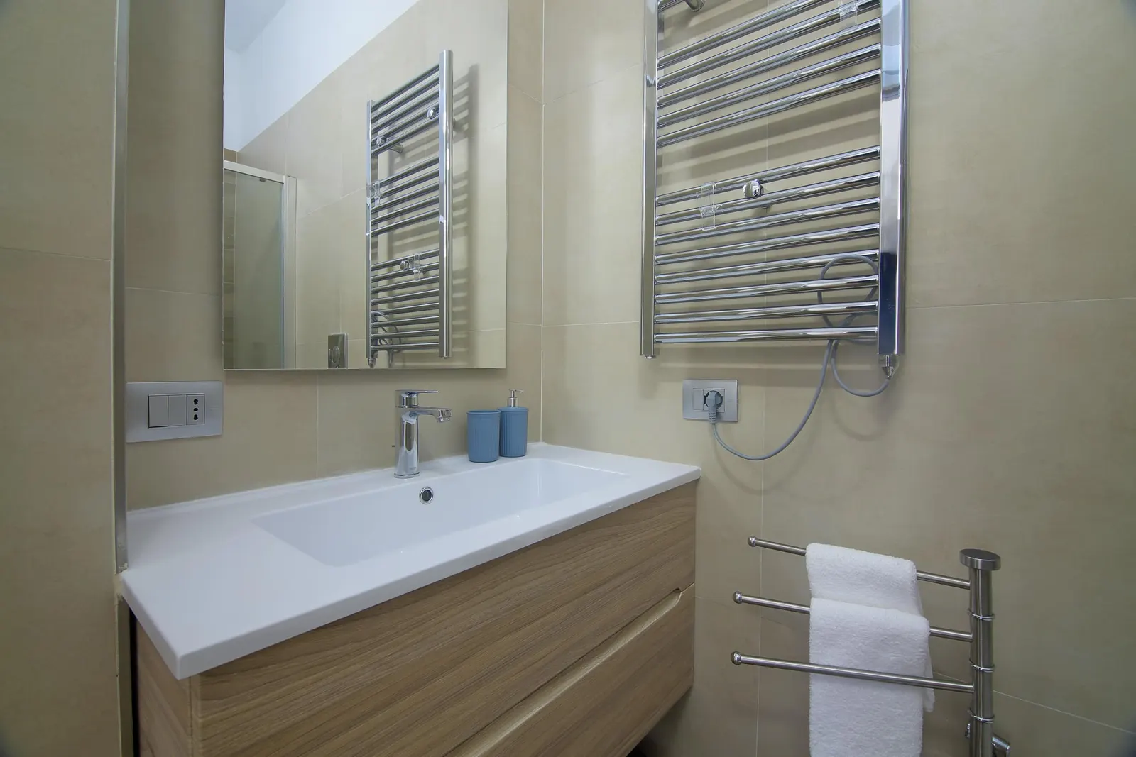 A bathroom washbasin with heated towel rail