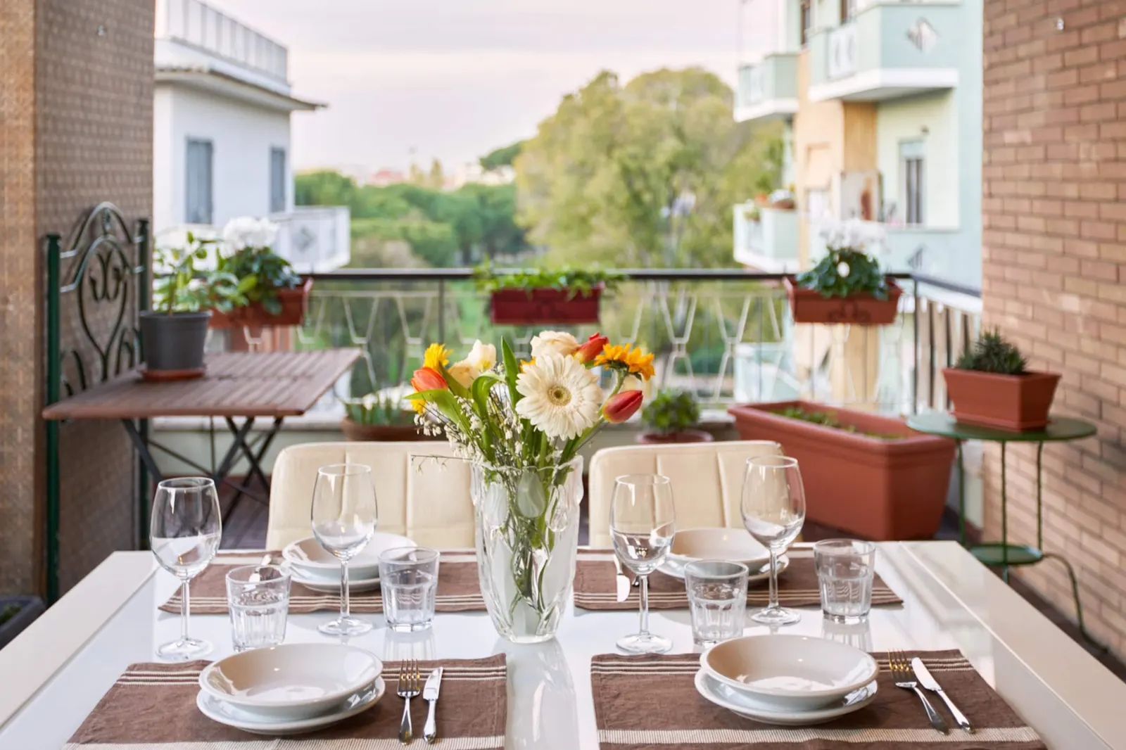 The terrace with a laid table, flowers and a view over buildings and trees