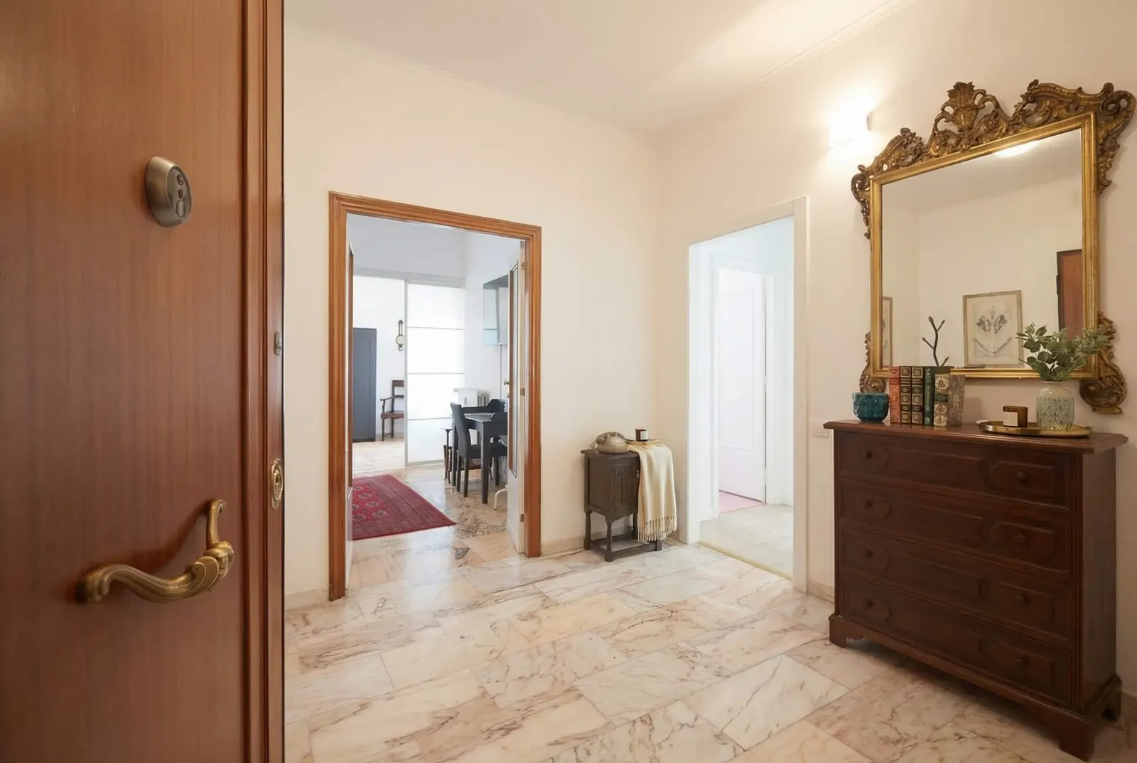 The front door opening onto the hall with the gilded mirror