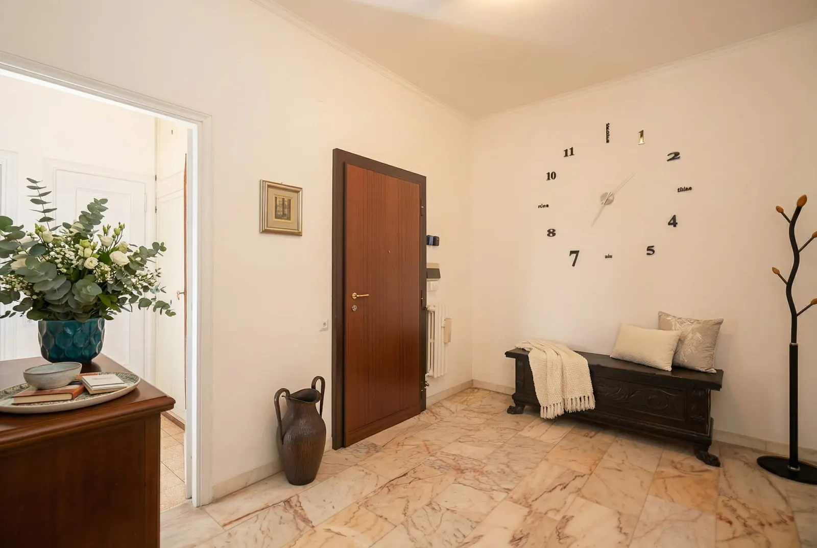 The entrance hall with a bench and a wall clock